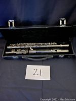 Full view of three-piece flute inside black carrying case with metal clasps.