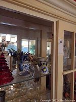 Photo of top shelf displaying ceramic teapots, teacups, saucers, and red glass Christmas tree