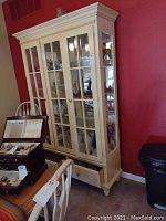 Front view of off-white china cabinet with glass doors and drawers open, showing shelves and interior lighting