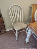Single wooden dining chair with contoured seat and curved slatted backrest, painted white with distressed finish.