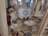 Glass cabinet shelf with porcelain trays and bowls including a blue floral Herend tray on a stand, Nippon tray, floral footed bowls