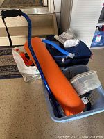 Photo of blue metal cane, orange foam roller and items packed in plastic basket