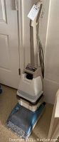 Full view of Hoover Steam Vac carpet cleaner upright with handle and power cord wrapped around it.