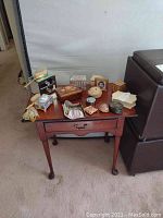 Photo showing four jewelry boxes and assorted grooming items on a wooden table next to a sofa, various shapes and sizes including wooden and mirrored boxes.