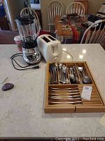 Countertop overview showing Cuisinart blender, Toastmaster toaster, and flatware set in wooden storage tray