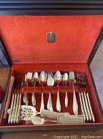Open anti-tarnish chest containing 58-piece Oneida silverplate flatware set with original papers, showing full set arrangement.