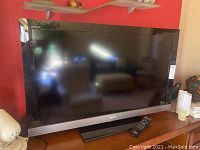 Front view of the Sony Bravia 48-inch flat screen TV on a wood surface, showing its large black screen and silver bottom bezel with Sony branding.
