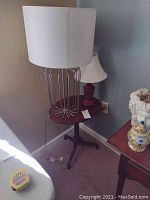 Side view of the mahogany colored tilting side table with two table lamps on top