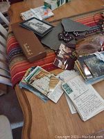 Top view showing scattered postcards, dominoes, jacks, and some photos including two of John Denver arranged on a table.