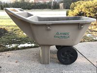 Side view of beige Ames Easy Roller Jr. garden cart showing the body, label, and one black wheel with wide tire.