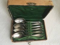 Six silver tea spoons arranged inside original green velvet-lined box showing interior condition and number of spoons