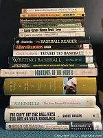 Side view of the first stack of assorted hard and softcover baseball books showing various titles and authors.