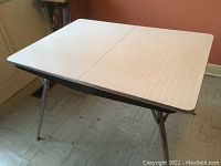 Full view of rectangular kitchen table with chrome legs and light-colored formica top featuring geometric pattern.