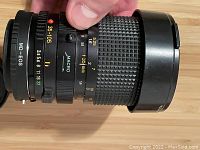 Side view of Minolta MD EOS 35-105mm camera lens showing zoom and aperture markings and macro feature.