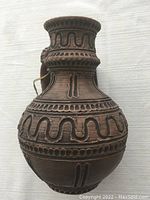 Side view of the vintage brown ceramic vase/jug showing embossed wave and dot patterns and narrow neck.