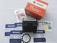 Viewmaster Model F viewer, 5 reels, original box, and instruction guide laid out on white surface.