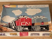 Original cardboard box with illustrated cover showing two locomotives, one red and black CN marked, and one grey Canadian Pacific locomotive, with text indicating exclusive manufacture for Simpsons and Simpsons-Sears.