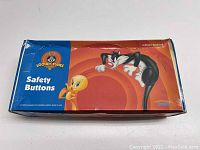 Closed box showing Looney Tunes logo, 'Safety Buttons' text and '6 Dozen Assorted'