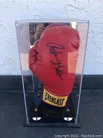 Front view of red Everlast glove inside clear display case showing clear signature.