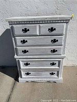 Full front view of the painted white Broyhill dresser showing five drawers with ornate black handles, decorative molding along top edge, and carved base detail.