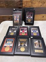 Photo showing multiple Highland Mint framed sports memorabilia pieces with gold plated coins and logos