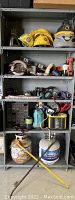 Full view of metal shelf with multiple shelves containing various tools and supplies including hardhats, shop vac, power tools, hardware drawers, propane tanks, and other items.