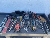 Wide angle photo showing an assortment of hand tools on garage table.