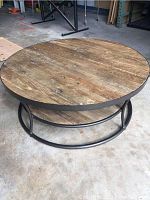 Front angled view showing round wooden top and metal frame supporting double levels of wooden planks