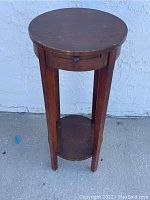 Round wooden table showing top, legs, and bottom shelf with visible wear and scratches.