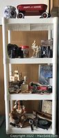 Full view of white plastic shelf unit filled with vertical view of items including Radio Flyer wagon model on top and binoculars on second shelf.