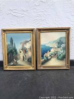 Two framed vintage paintings side by side on ground against wall, showing full view and frames