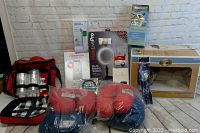 Wide view of all assorted merchandise including boxing gloves, cooler bag, and boxed electronics on table