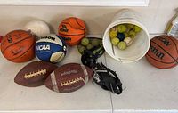 Overview of all balls showing basketballs, footballs, volleyball, and bucket with tennis balls