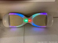 Front view of the black Jetson Plasma hoverboard with multicolor LED lights turned on and non-slip beige footpads.