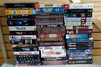 Long stack of DVD box sets, mostly TV shows, organized vertically. Visible titles include Newsroom, True Blood, 24, Heroes, Grey's Anatomy, Rome, Friends, Nip/Tuck, Planet Earth, Entourage, Matlock, Dragnet, and others.