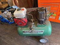 Side view of green Speedaire air compressor tank, Honda red engine, and pressure gauges.