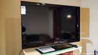 Front view of a black 40-inch Samsung LCD TV placed on a clear surface with its remote control.