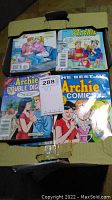 Photo showing a box containing multiple Archie comic digest books with visible colorful covers featuring classic Archie characters in social scenes.