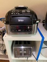 Ninja Air Fryer Smart Grill sitting on shelf with Cuisinart toaster below.