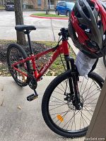 Full side view of the red Smart bicycle with helmet resting on the handlebars.