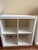 Front angle view of white laminated cube shelf showing four square compartments.