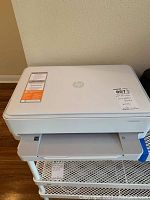 White HP Envy 6000C series printer from an angled front view showing top and front paper tray.
