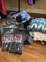 Pile of assorted ladies t-shirts, workout pants, and shorts in various colors and patterns, some packaged in plastic.