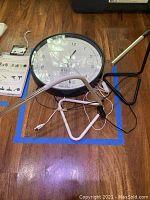Photo showing two USB desk lamps with metal LED light heads and adjustable flexible necks placed around a round 15-inch metal wall clock with black frame and white face.