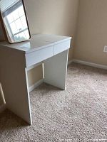 White laminate vanity with mirror placed on top, photographed from front angle showing full view of vanity