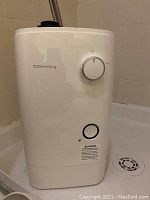Front view of white Coway water softener with control dial and brand name visible.