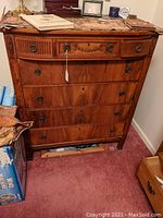 Full front view of the tall dresser showing 7 drawers with round metal pulls and decorative details on top drawers.