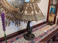 Full view of lamp on table showing painted bronze base and two-tone slag glass shade