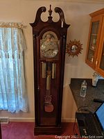 Full height front view of grandfather clock showing case, dial, weights and pendulum