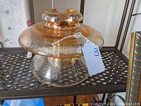 Photo of the large carnival glass insulator showing overall shape and color on a dark metal shelf.